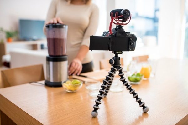 A close up of a young woman vlogging herself whilst preparing a smoothie